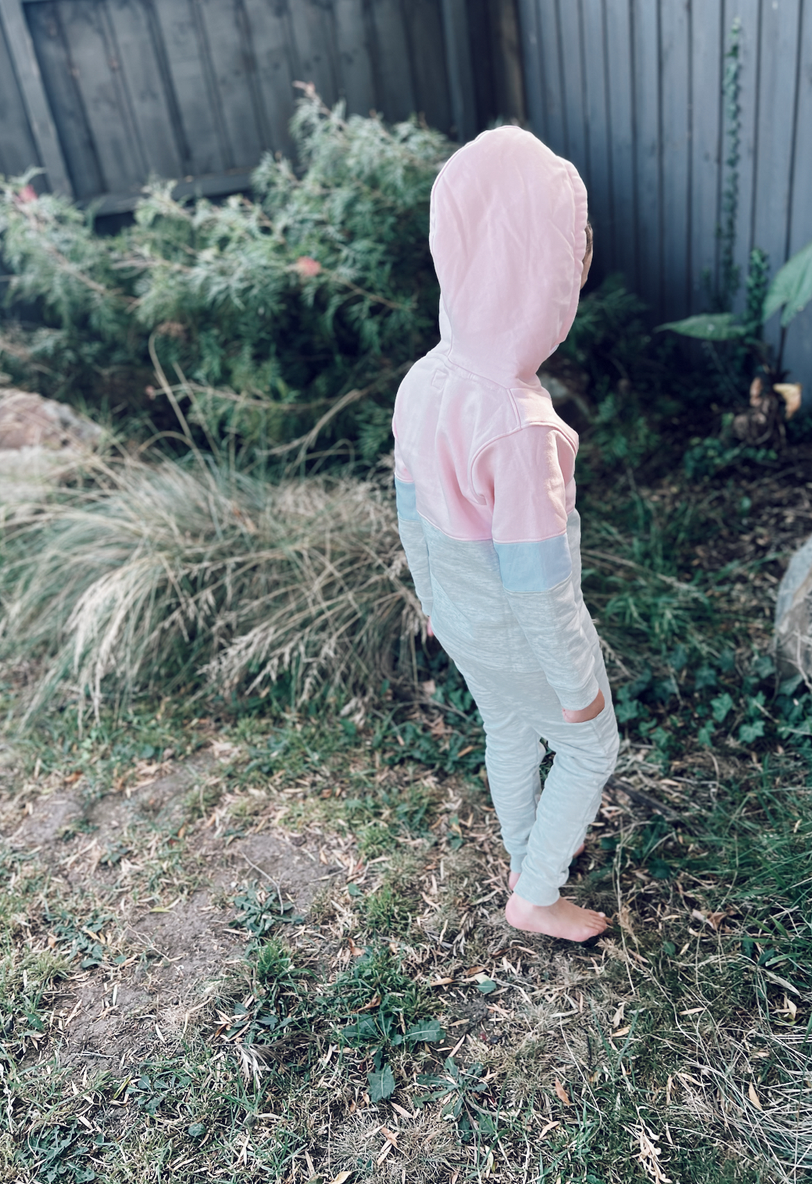 Child wearing matching tracksuit walking toward garden