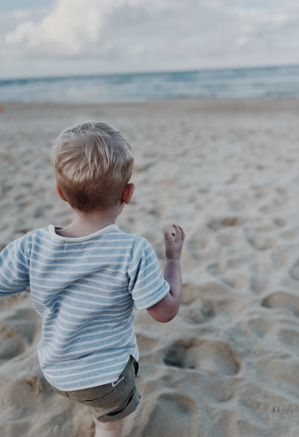 child in blue stripe tee on beach