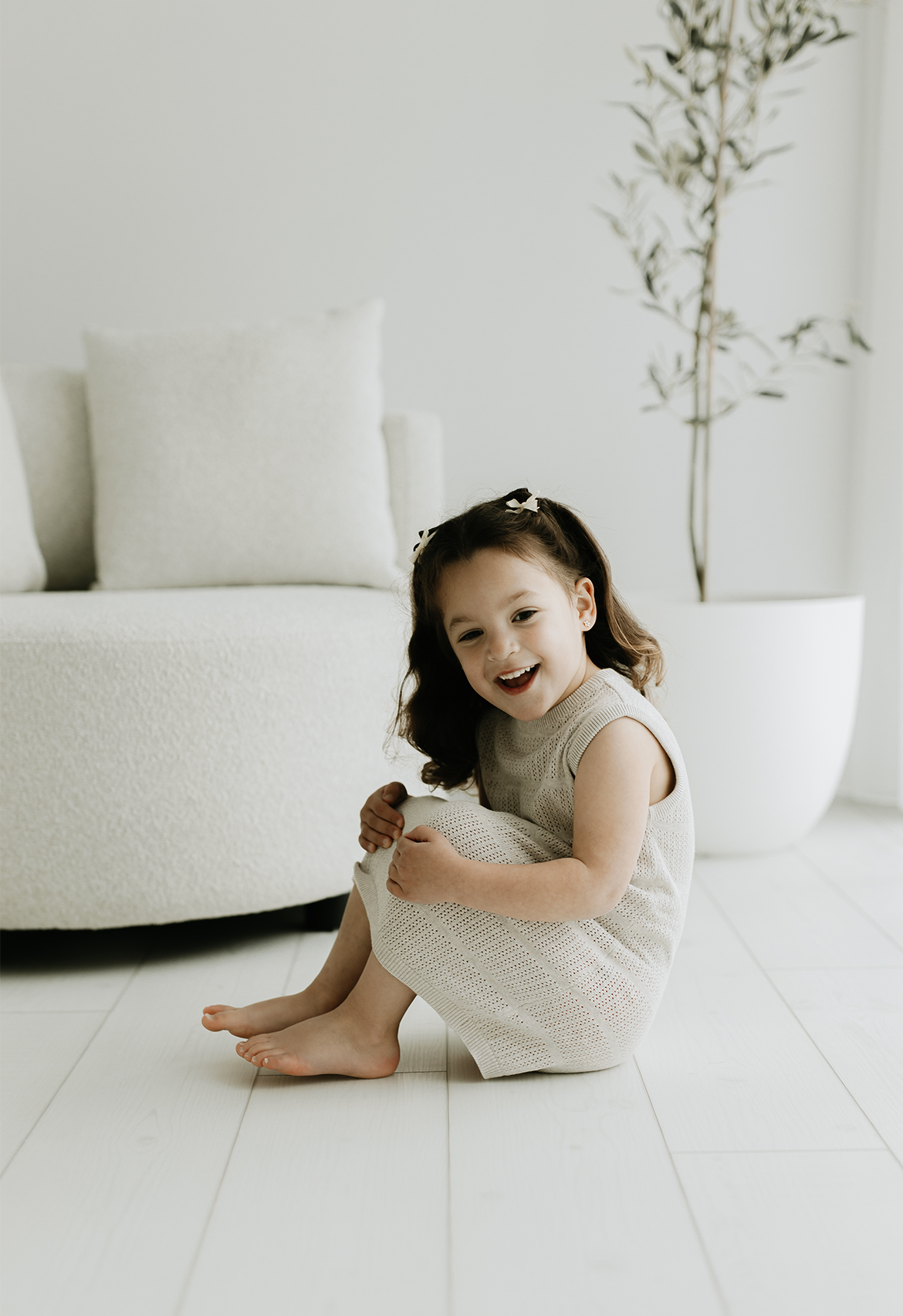 toddler sitting in white photography room in stone marle pointelle dress