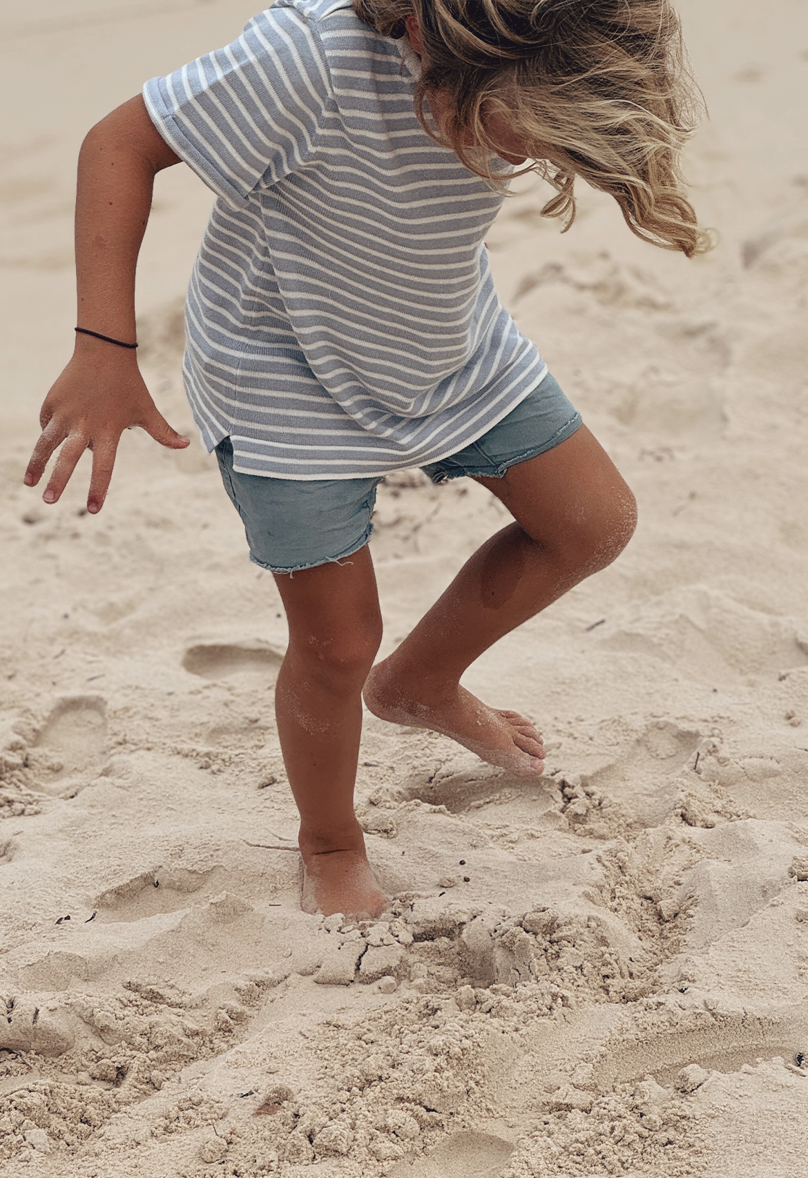 boy on sand in stripe knit t shirt