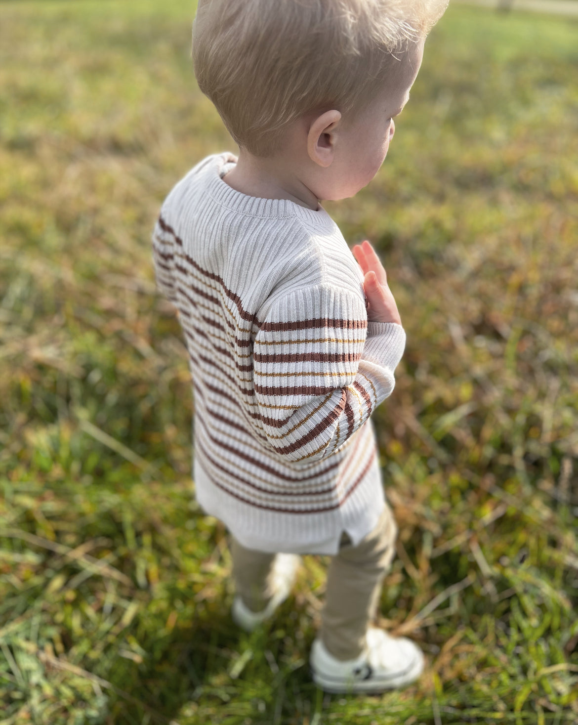 boy in field close up of ribbed striped neutral toned jumper