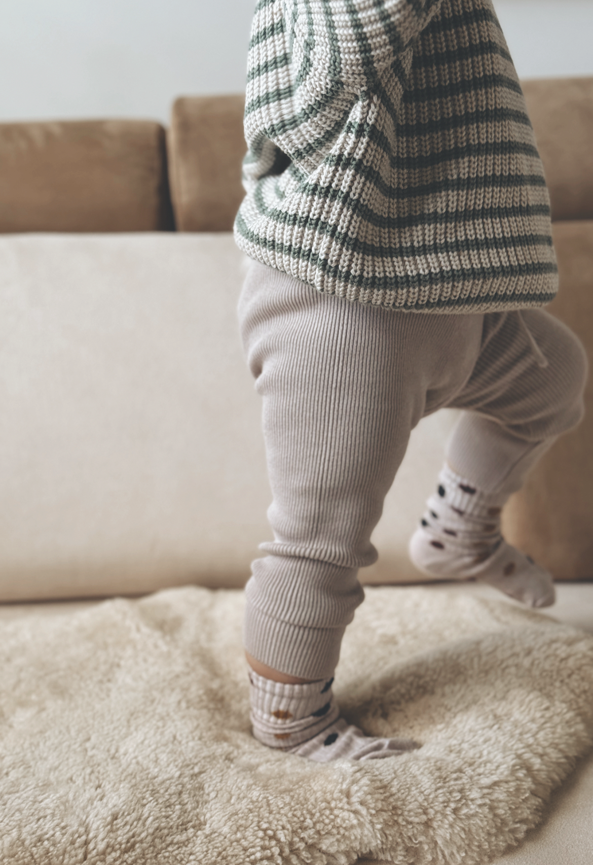 Baby wearing legging in stripe knit jumper and polka dot sock.