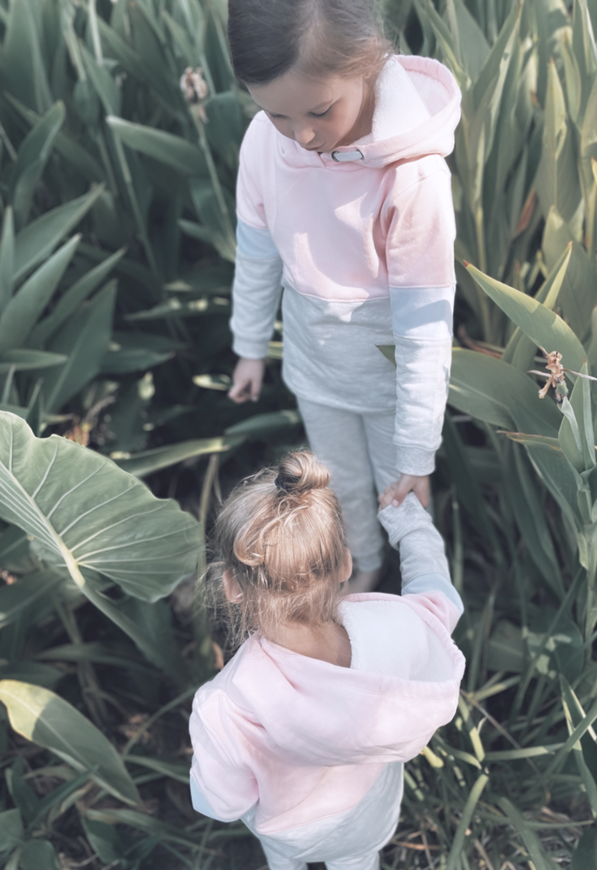 sisters exploring the garden wearing organic cotton block hooded jumpers.